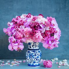 a blue and white vase filled with pink flowers