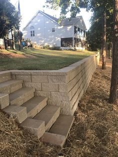 a stone wall with steps leading up to the front door and side yard in the background