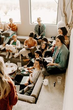 a group of people sitting on couches in a living room with lots of windows