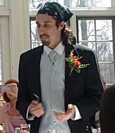 a man in a tuxedo standing next to a woman at a dinner table