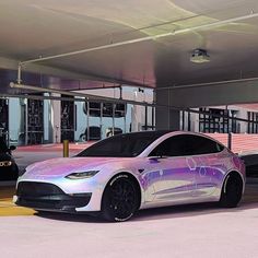 a silver car parked in a parking lot next to another car with pink and purple paint on it