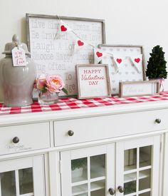 valentine's day decorations are displayed on top of a china cabinet