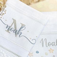 two embroidered napkins with the words noah and noah written in silver thread on them