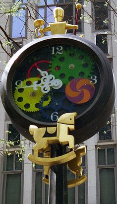 a large clock that is on the side of a pole in front of a building