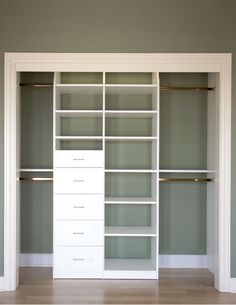 an empty walk in closet with white shelves and drawers on each side, against the wall