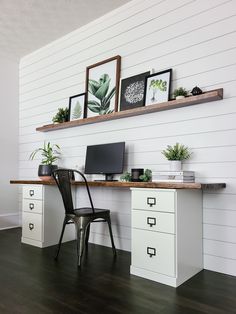 a desk with a computer on top of it next to a chair and potted plants