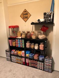 a shelf filled with lots of candy next to a game zone sign on the wall