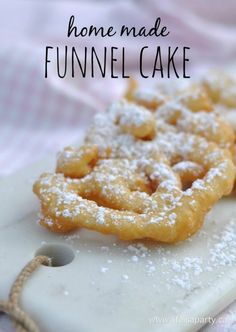 homemade funnel cake with powdered sugar on top sitting on a cutting board, ready to be eaten