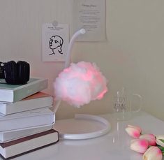 a cloud lamp sitting on top of a table next to some books and flowers in a vase