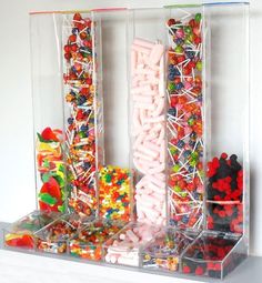 several different types of candies in clear plastic containers on a white shelf next to each other