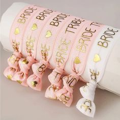 pink ribbon with gold foiled letters and bows on it, sitting in front of a white tube