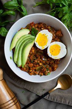 a bowl filled with beans, eggs and avocado on top of a table