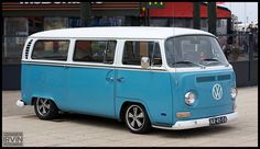 an old blue and white vw bus parked in front of a building