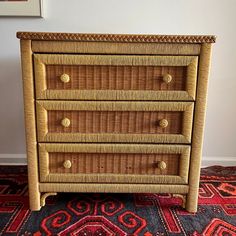 a wicker dresser with four drawers on top of it and a rug in front of it