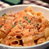 a white bowl filled with pasta and sauce on top of a checkered table cloth