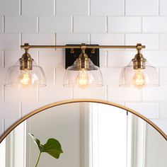 a bathroom vanity light with three clear glass globes on the top and one gold frame