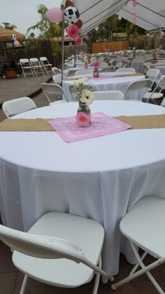 tables with white chairs and pink tablecloths are set up for an outdoor event