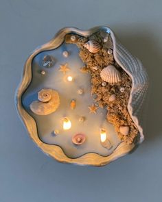 seashells and candles in a bowl on a table