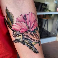 a woman's arm with a turtle and flower tattoo on it