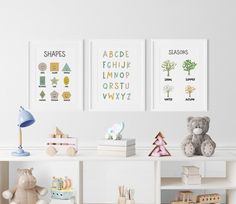 three children's art prints on the wall above a bookshelf with toys