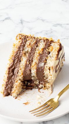 a piece of cake on a white plate with a gold fork next to the slice