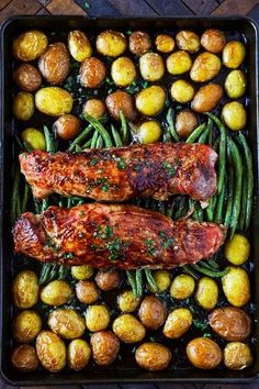 two meats and green beans in a roasting pan with potatoes on the side