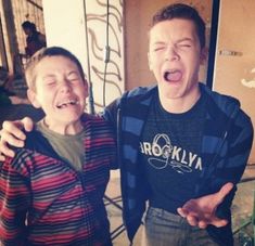 two young boys standing next to each other in front of a door with their mouths open