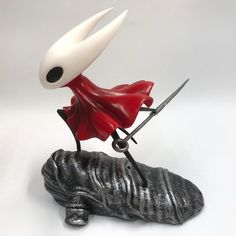 a small figurine with a red cape on top of a black object that looks like a shoe