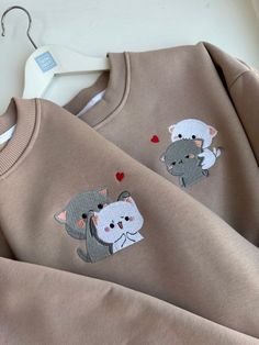 two sweaters with animals on them sitting next to each other, one has a heart and the other has an elephant