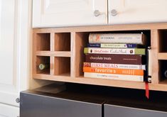 several books are stacked on top of each other in a book shelf next to a refrigerator