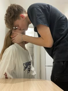 a man kissing a woman on the cheek in front of a table with a refrigerator