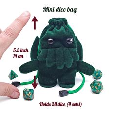 a hand is pointing at a stuffed animal with dices in it's mouth