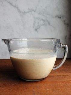 a glass bowl filled with batter on top of a wooden table