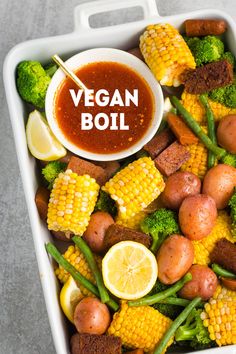 a tray filled with corn, potatoes and broccoli next to a dipping sauce