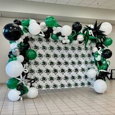 a balloon arch decorated with black, white and green balloons for st patrick's day