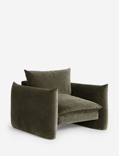 an olive green velvet lounge chair with two pillows on the back and one arm folded