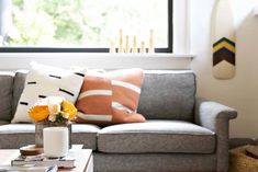 a living room with a couch, coffee table and vase filled with flowers on it