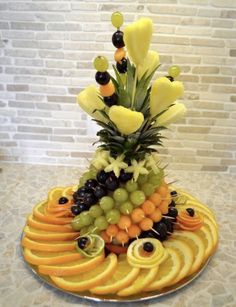 a fruit platter with grapes, oranges, and pineapples on it