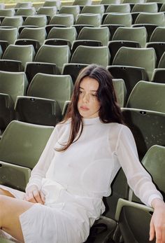 a woman sitting on a chair in an empty stadium