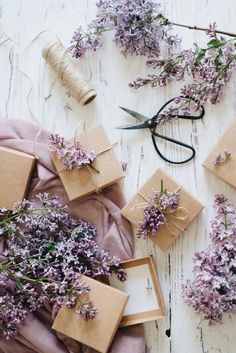 lavender flowers and twine tied to brown boxes on a white wooden table with scissors