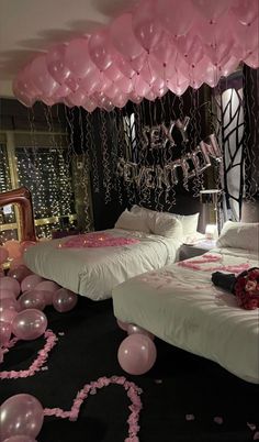 two beds in a room with balloons and streamers