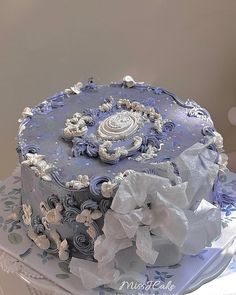 a blue and white decorated cake on top of a table with paper doily around it