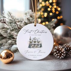 a christmas ornament with a house on it next to pine cones and ornaments