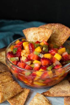 fruit salsa in a glass bowl surrounded by crackers