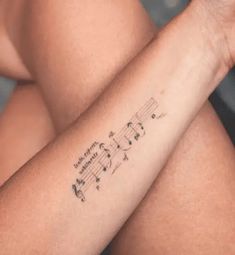 a woman's arm with musical notes tattooed on the left side of her arm