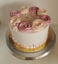 a white cake with pink and gold frosting flowers