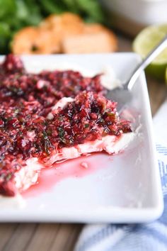 a white plate topped with meat covered in cranberry sauce and garnish