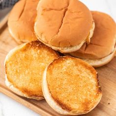 three hamburgers sitting on top of a wooden cutting board