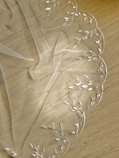 a piece of white sheer fabric with leaves on it