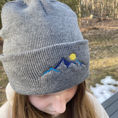 "Keep your head and ears warm this winter with our stylish mountain beanie hat! The cuff features a beautiful embroidered design of mountains and a moon, making it the perfect finishing touch to any winter outfit. Made from 100% acrylic, this hat is sure to keep you cozy all season long. 100% acrylic knit 12\" knit Adjustable cuff, shown as 3\"" Gray Warm Beanie For Outdoor, Warm Gray Beanie For Outdoor, Winter Hats For Outdoor Activities, Outdoor Beanie Cap, One Size Fits Most, Gray Winter Hats For Outdoor, Gray Winter Outdoor Hats, Winter Outdoor Hat With Adjustable Fit, Warm Hats For Winter Outdoor Activities, Adjustable Winter Hats For Outdoor Activities